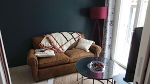 A living room with a brown sofa, a glass coffee table, and a red floor lamp.