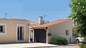 A residential building with a beige facade, a tiled roof, and a garage door.