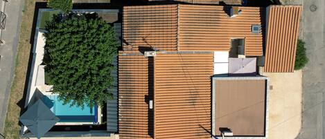 Vista aérea de un barrio residencial con varios edificios, una piscina y un árbol grande.