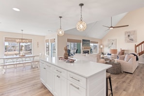 A spacious kitchen with a large island, pendant lights, and a ceiling fan. - Fish On | 5BR Canal Home · Private Boat Dock · Golf Cart & Bikes Included (Ocean Isle Beach)