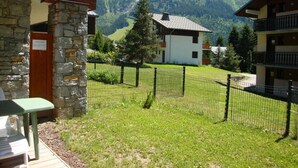 A view of a mountain landscape with a building featuring a stone facade and a balcony.