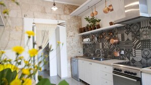 A modern kitchen with a stone wall, stainless steel appliances, and patterned tiles. - Villa Angela | Beautiful Villa with Pool in Puglia in Polignano a Mare, Italy (Polignano a Mare)