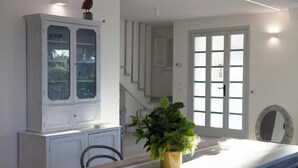 A dining area with a white cabinet, a potted plant, and a staircase leading to a second floor. - Villa Angela | Beautiful Villa with Pool in Puglia in Polignano a Mare, Italy (Polignano a Mare)