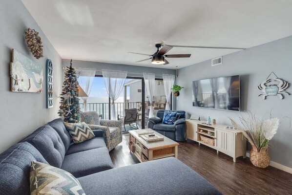 A modern living room with a grey sofa, a coffee table, a TV, and a ceiling fan.