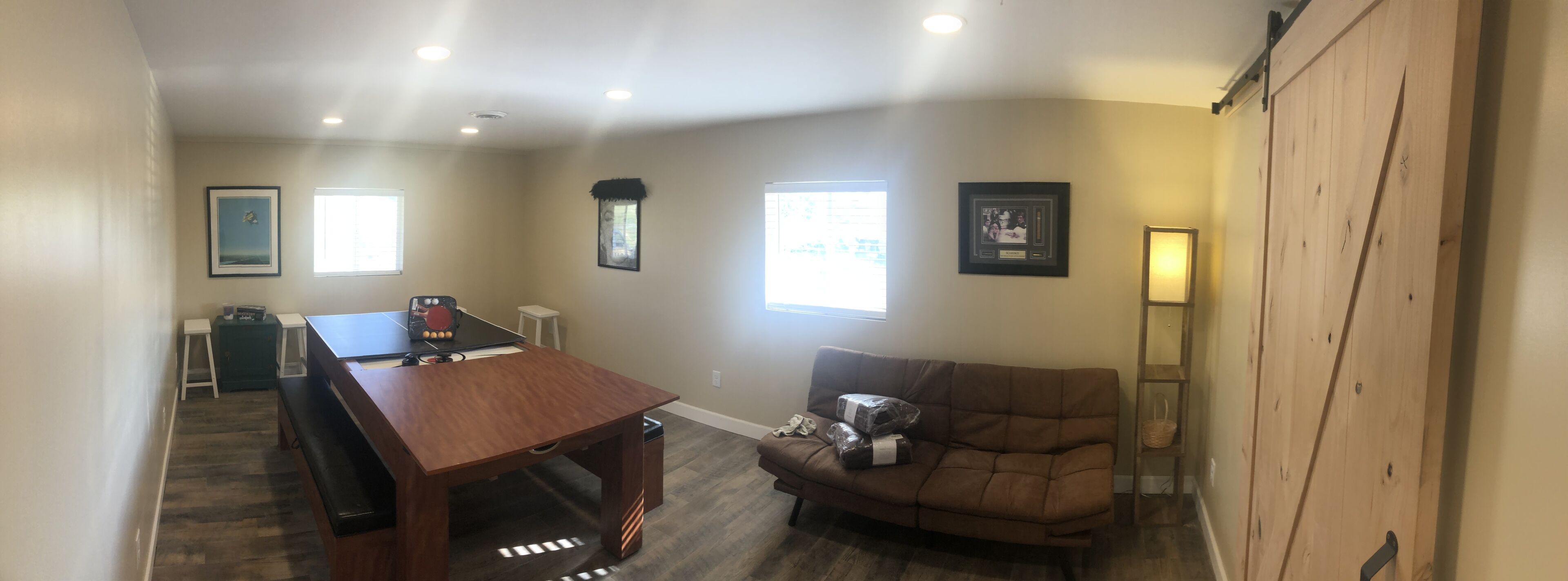 A living room with a wooden table, a brown sofa, and a large window.