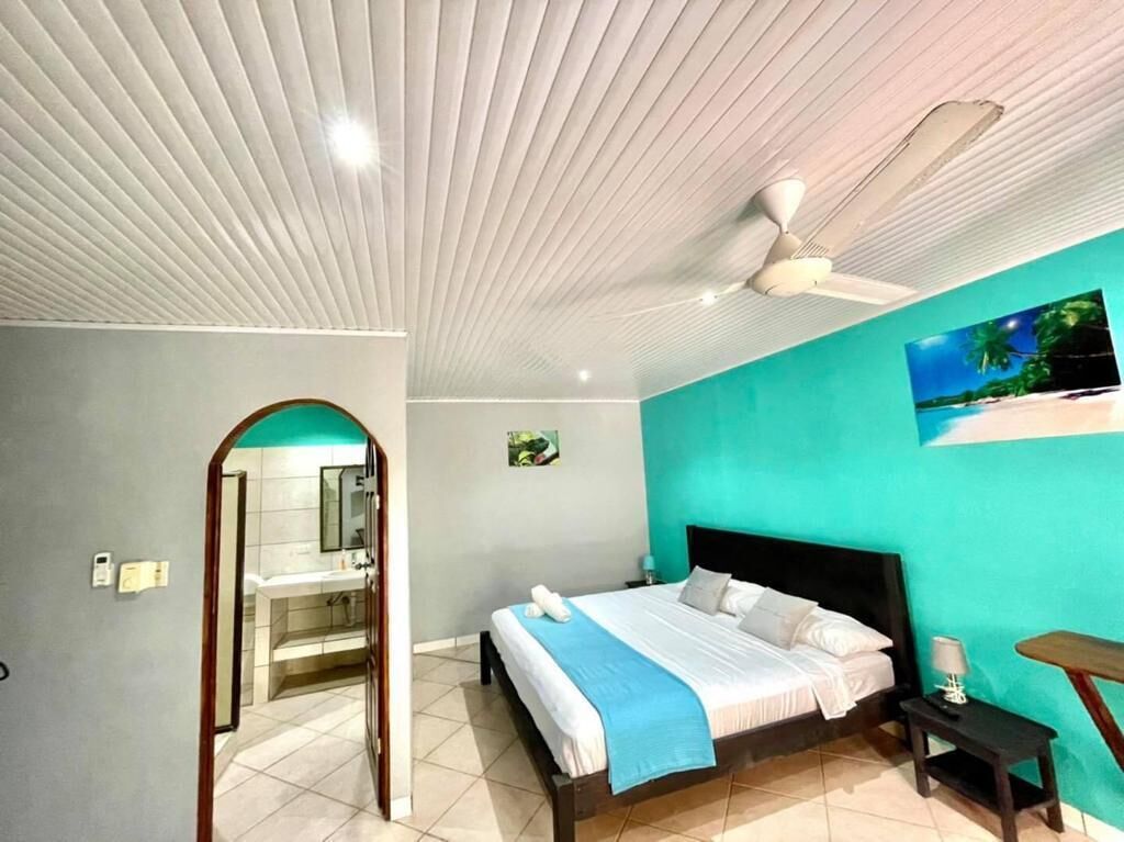 A bedroom with a bed, a ceiling fan, a nightstand, and a wall-mounted TV.
