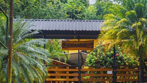 A set of stone steps leading to a building with a wooden fence and a sign that reads "LOMBRI". - Hotel Colibri (Quepos)