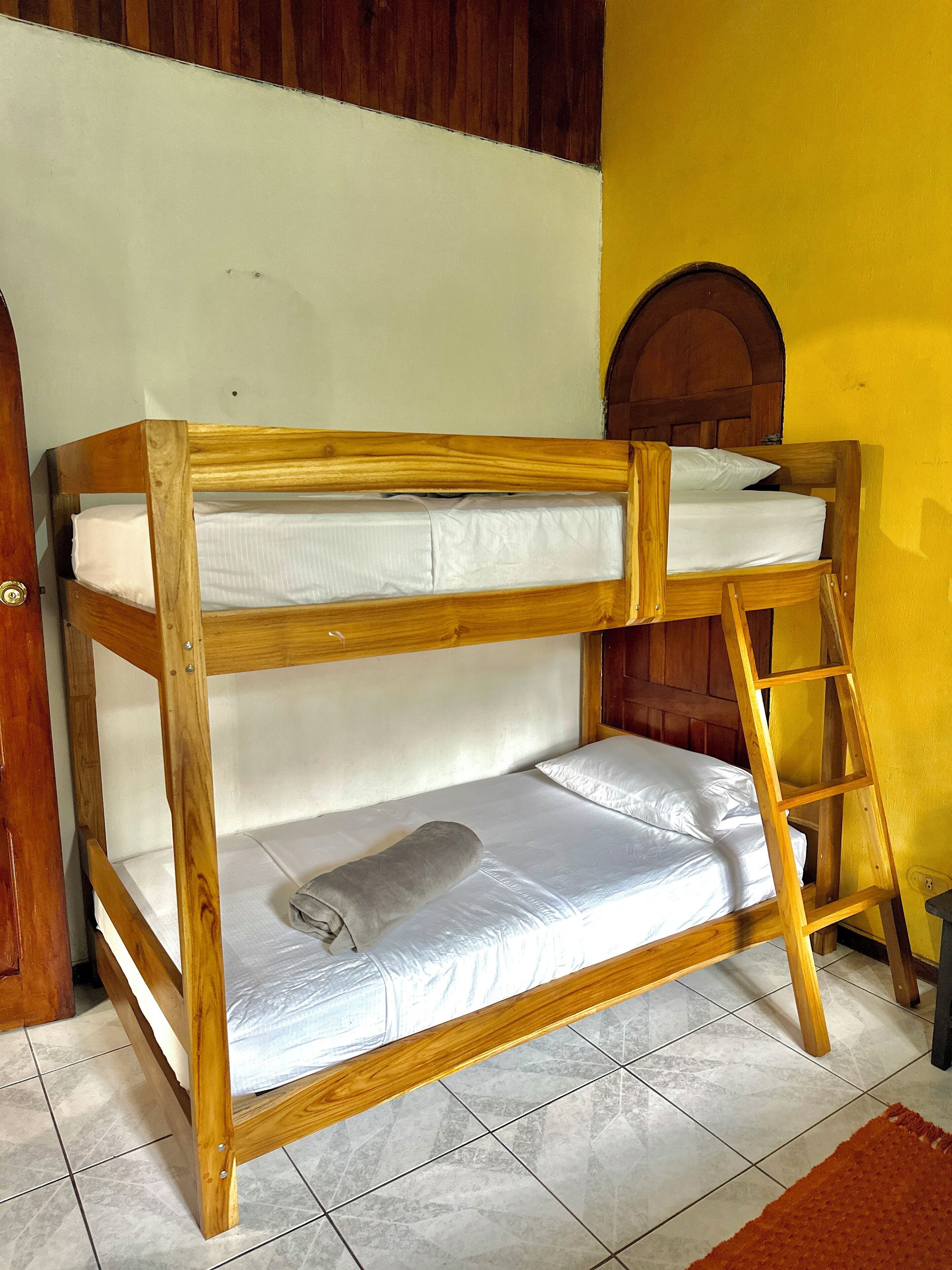 Una cama individual con estructura de madera, ropa de cama blanca y una escalera.