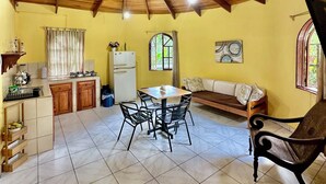A spacious kitchen with a dining area, wooden ceiling beams, and a tiled floor. - Hotel Colibri (Quepos)
