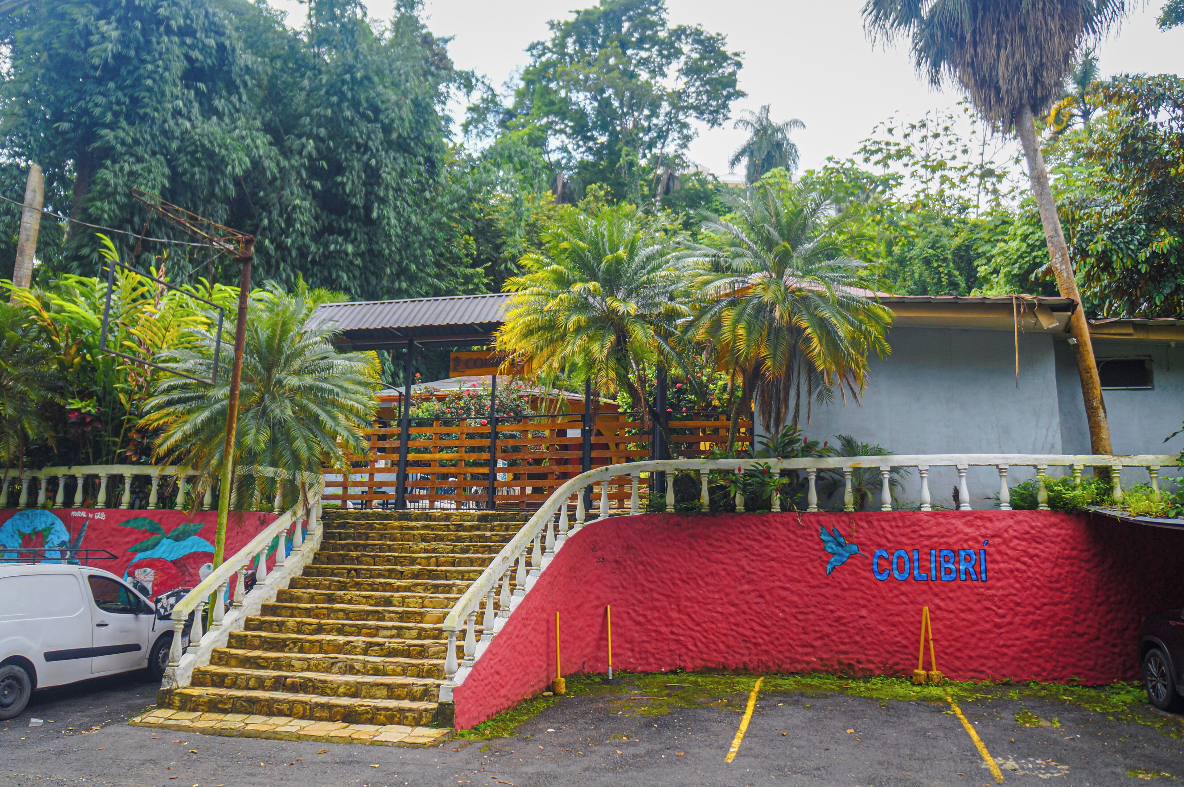 Escadaria que leva a um edifício com parede vermelha e a palavra "COLIBRI" escrita nela.
