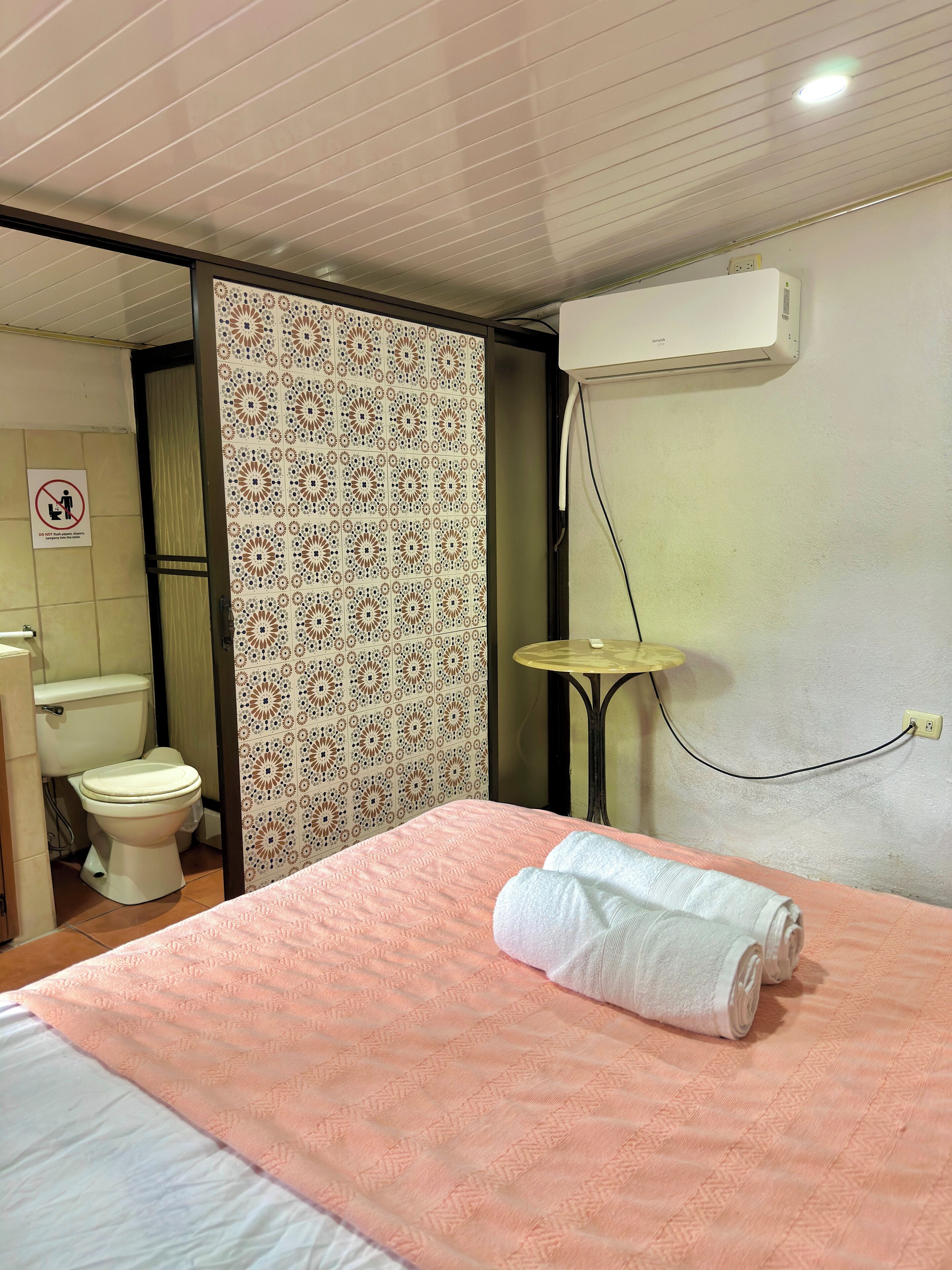 Ein Hotelzimmer mit Bett, Toilette und Klimaanlage.