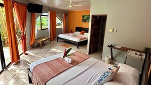 A hotel room with a large bed, a bench, a massage table, and a view of the outdoors. - Hotel Colibri (Quepos)