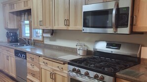 A kitchen with wooden cabinets, stainless steel appliances, and a window with a view.