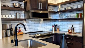 Une cuisine moderne dotée d’un four à micro-ondes encastré, d’appareils électroménagers en acier inoxydable et d’un grand îlot central avec un évier.