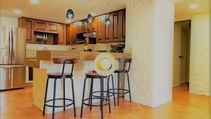 Une cuisine moderne avec des meubles en bois, un plan de travail en marbre et des tabourets de bar noirs.