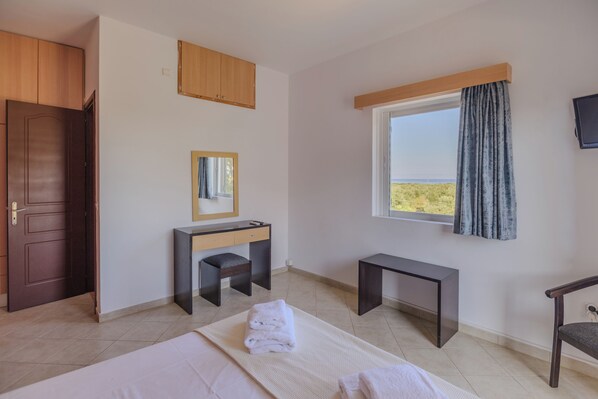 A room with a bed, a desk, a chair, a window with a view, and a door. - Stomio Villague (Trifylia)