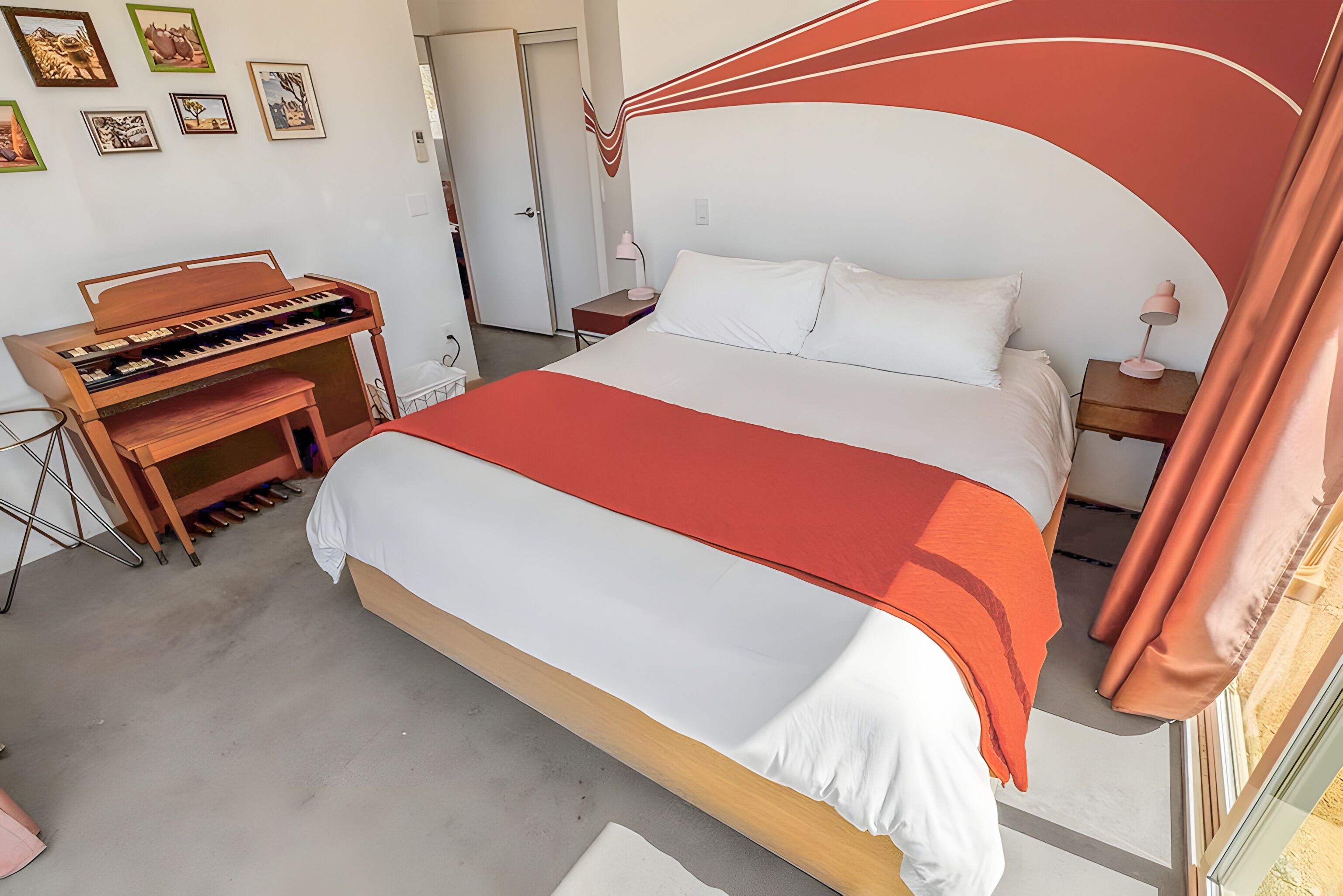 Ein Schlafzimmer mit einem Bett, einem Holzpiano und einer Tür.