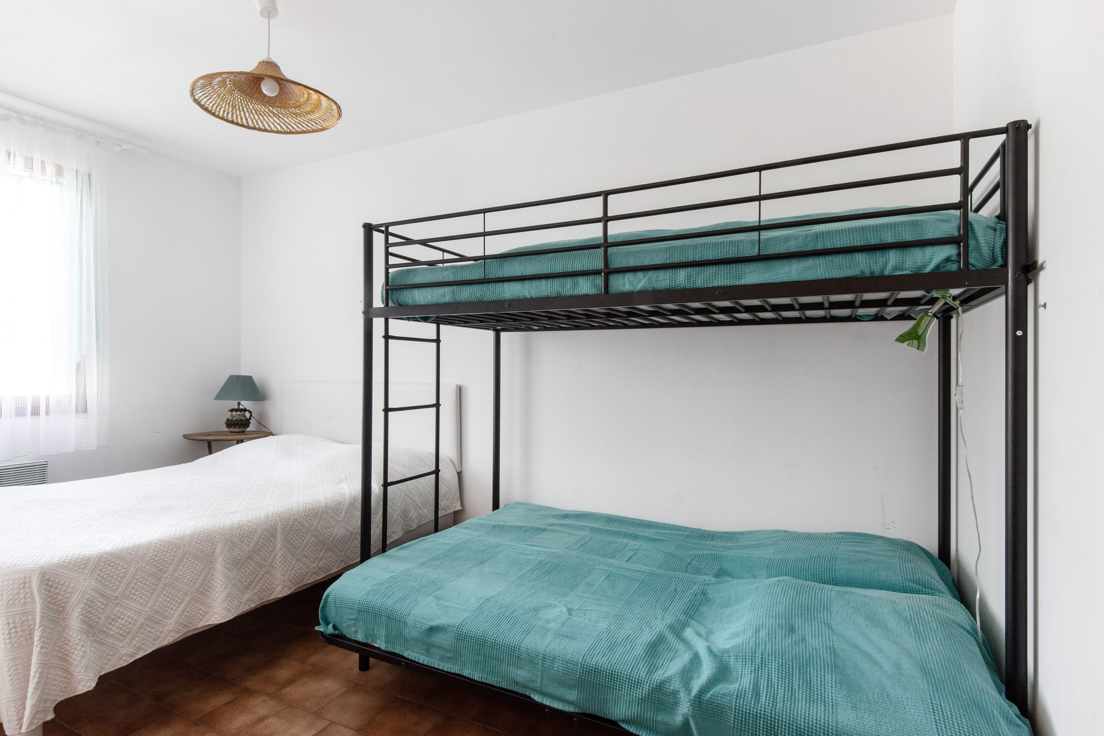 Habitación con literas, una cama blanca a la izquierda y una cama verde a la derecha.