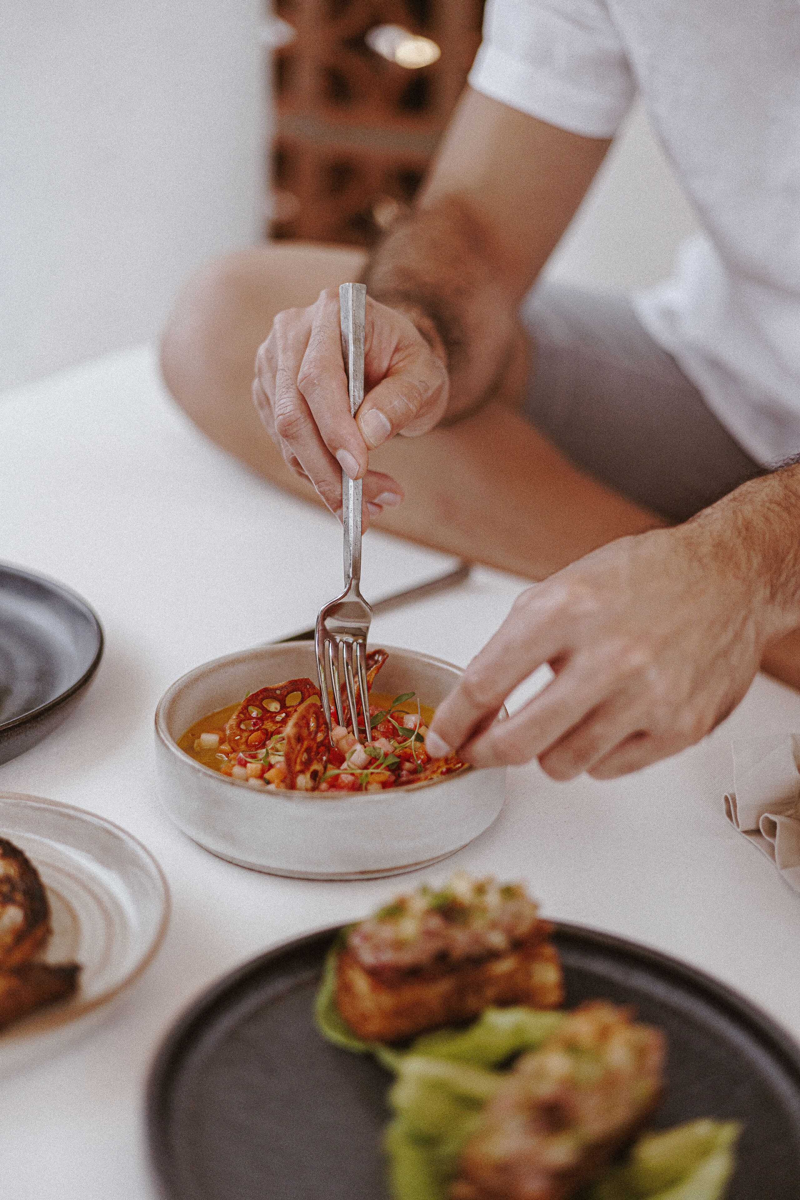 Una persona comiendo un plato de sopa con un tenedor.
