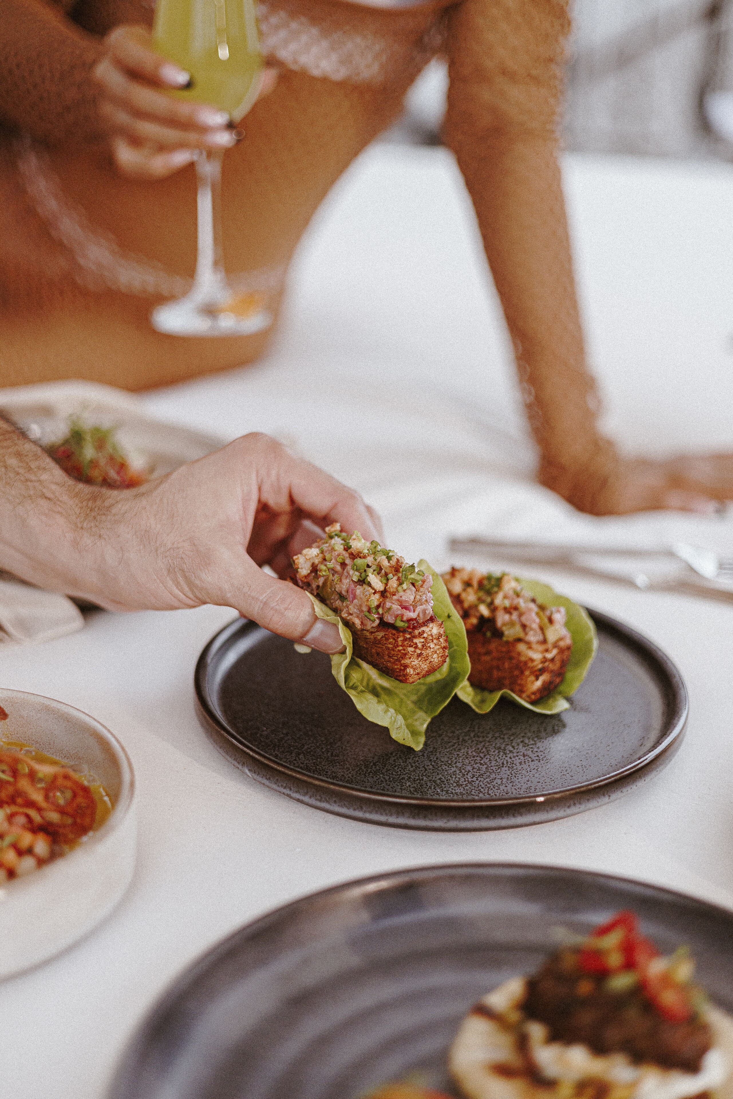 A person holding a food item with a green leaf on a plate.