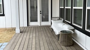 Eine überdachte Veranda mit Deckenventilator, einem Bett und einem kleinen runden Tisch.