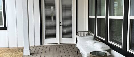 Une véranda couverte avec un ventilateur de plafond, un lit et une petite table ronde.