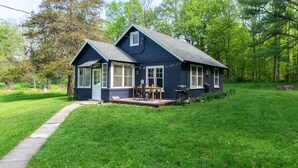 A small, dark blue house with a porch, a table, and chairs. - Whimsical Woodland Cottage in Stone Ridge NY (Stone Ridge)