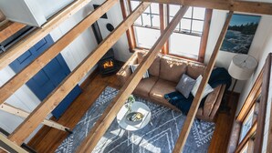 A room with exposed wooden beams, a blue door, a sofa with cushions, a patterned rug, and a fireplace. - Whimsical Woodland Cottage in Stone Ridge NY (Stone Ridge)