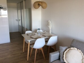 A dining area with a white table set for four, white chairs, and a hanging light fixture.