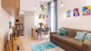 Un salon moderne avec un canapé, une table à manger et des chaises, ainsi que des œuvres d’art accrochées aux murs.