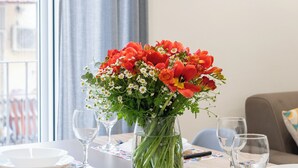 Une table à manger dressée avec des assiettes, des verres et un vase de fleurs.
