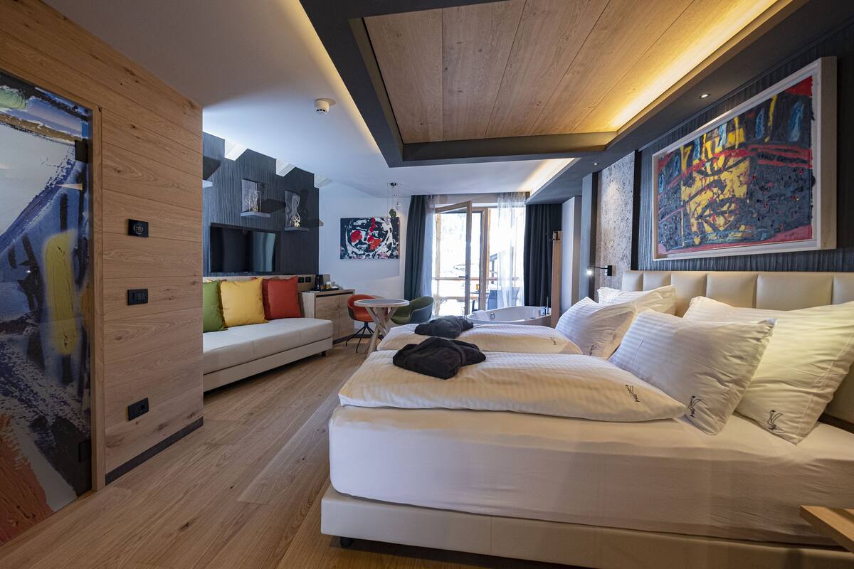 A modern bedroom with a large bed, a sofa, and a dining area.