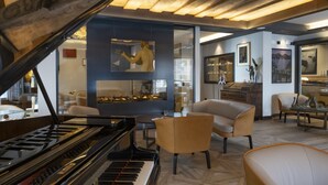 A modern living room with a grand piano, comfortable seating, and a large mirror reflecting the space. - Art Hotel Locanda degli Artisti (Canazei)