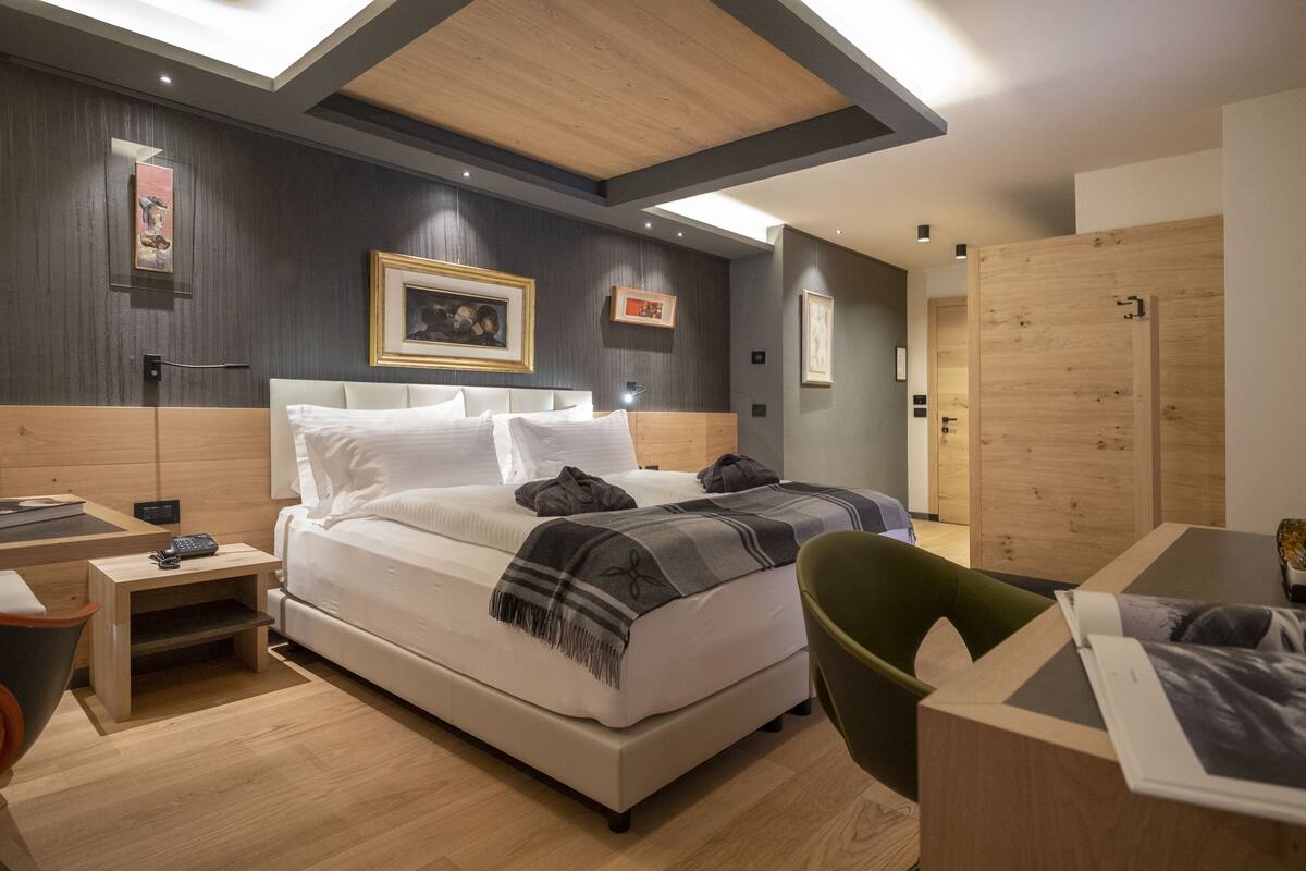 A modern bedroom with a large bed, bedside tables, a desk, and a chair.