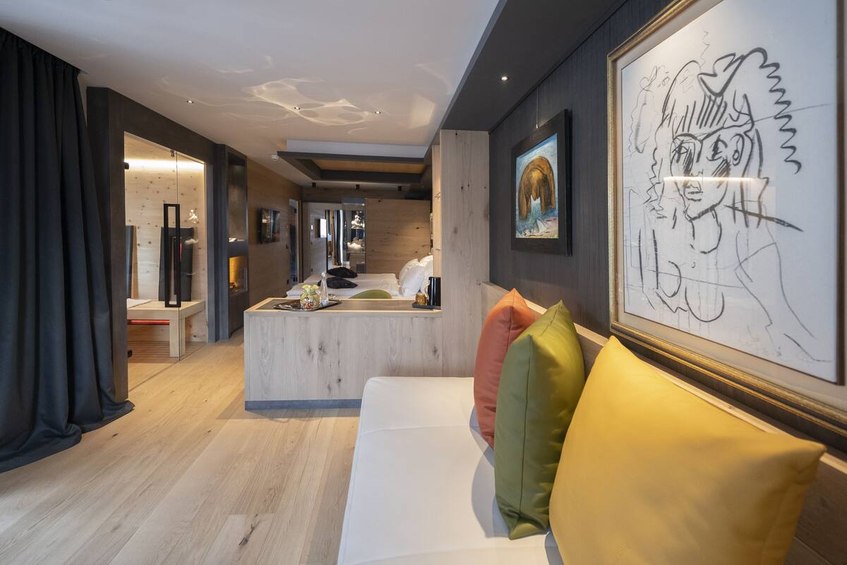 A modern interior with a central island, a white sofa with colorful cushions, and artwork on the walls.
