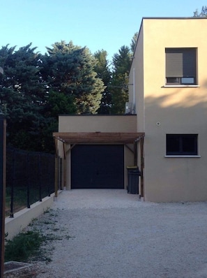 Un bâtiment moderne doté d’une entrée de garage couverte, d’une petite fenêtre et d’une allée gravillonnée.