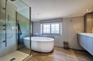 Een bad/douchecombinatie, handdoeken, toiletpapier