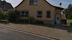 A two-story house with a sloped roof, a satellite dish, and a brick foundation. - Double room at Ferienwohnung Kilian (Weberstedt)