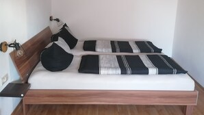 A single bed with a wooden frame and a headboard, white bedding, and black and white striped pillows. - Double room at Ferienwohnung Kilian (Weberstedt)