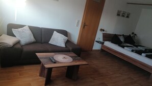 A living room with a sofa, a coffee table, a bed, and a door. - Double room at Ferienwohnung Kilian (Weberstedt)
