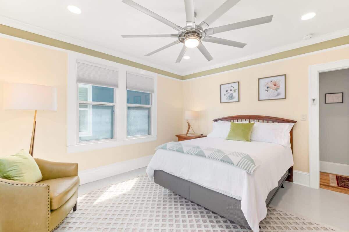 Un dormitorio con una cama, ventilador de techo, ventana y puerta.