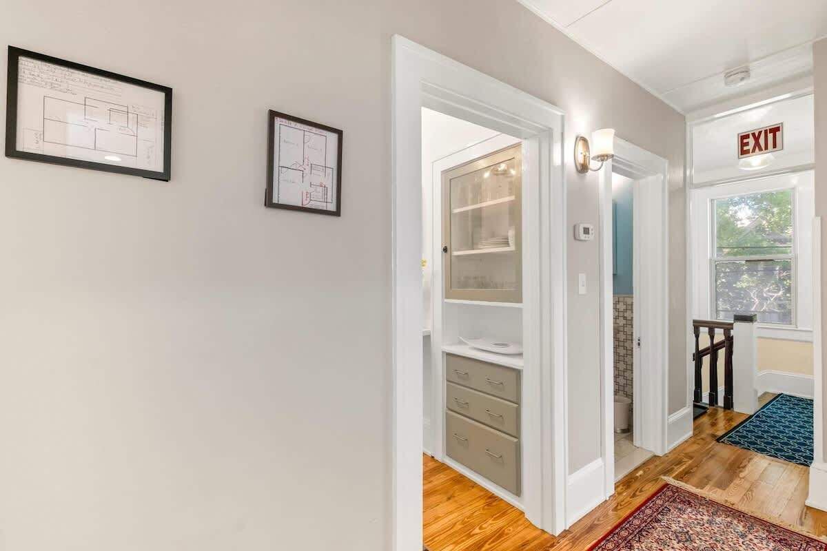 A hallway with a wooden floor, a blue rug, and an exit sign.