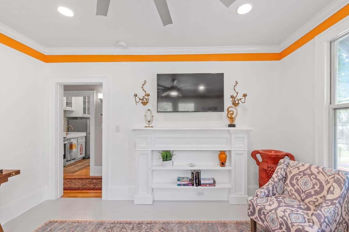 A living room with a white fireplace, a television above it, and a patterned sofa.