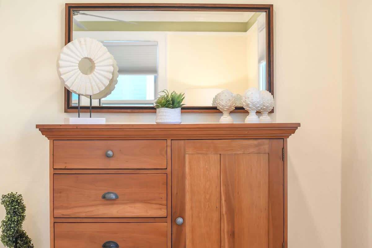 A wooden dresser with a mirror above it, a small potted plant, and decorative items on the dresser's surface.
