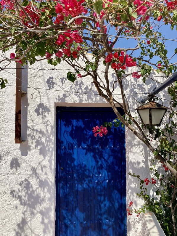 Une porte bleue, un mur blanc et un lampadaire à proximité.