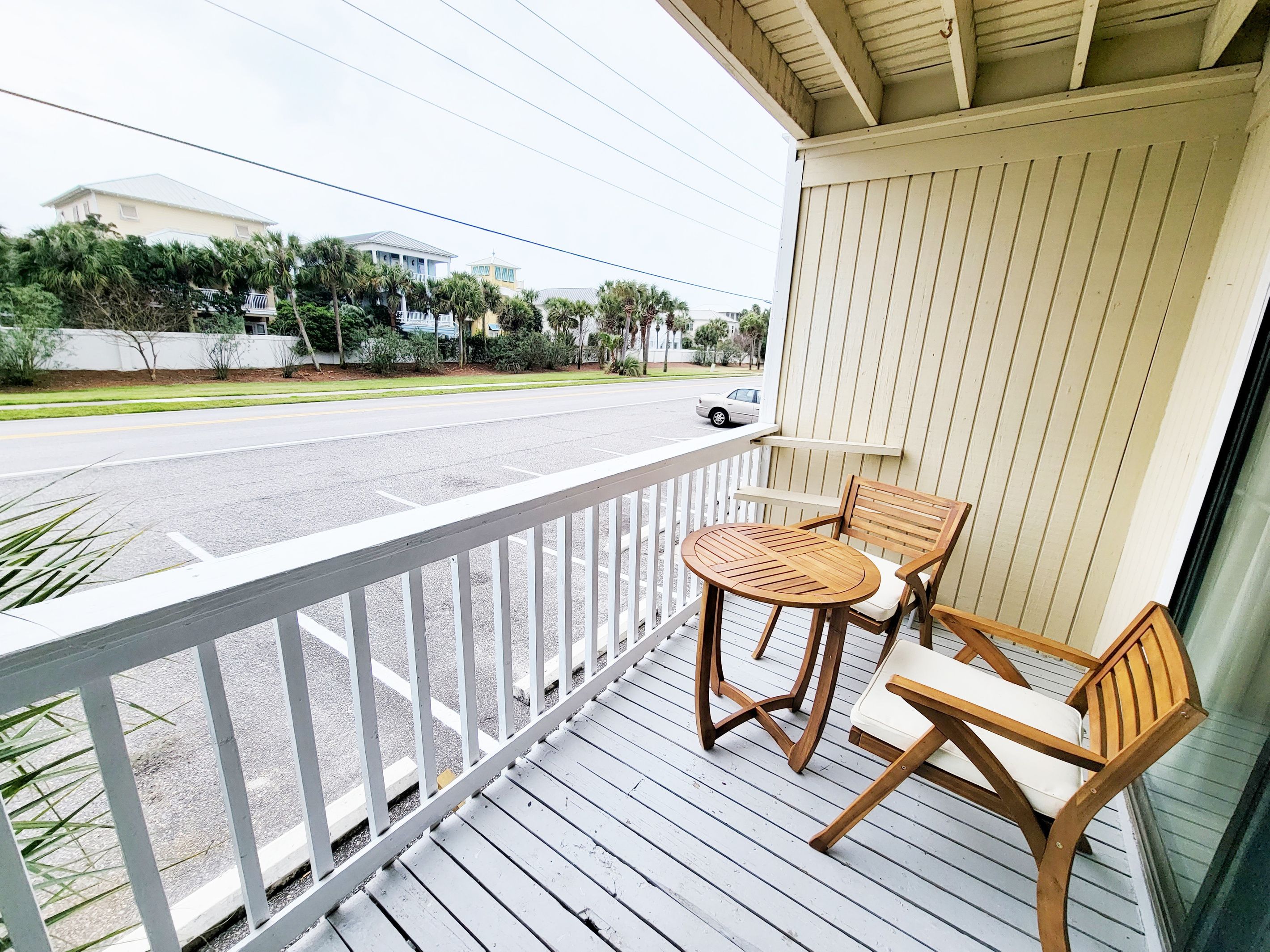 A wooden deck with a white railing, a round table, and two chairs.