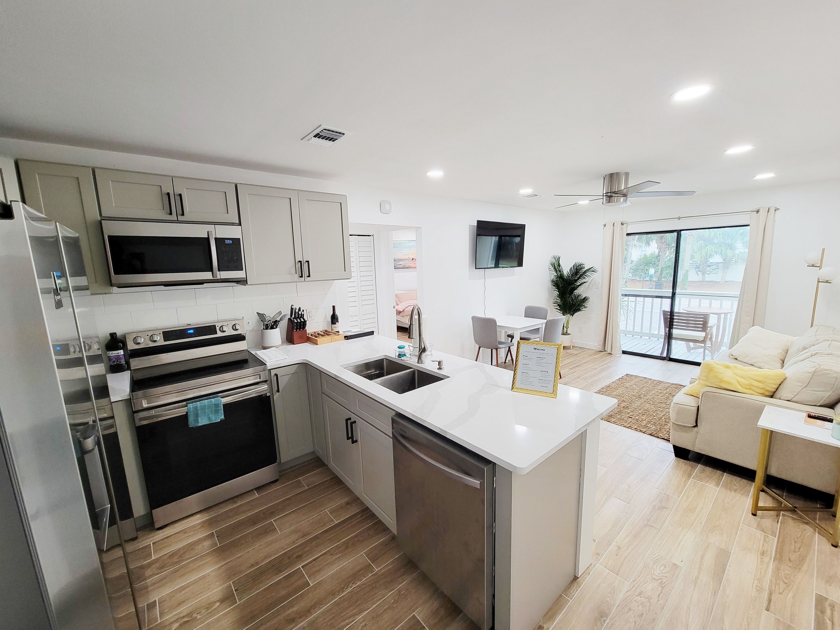 A modern kitchen with built-in appliances, a dining area with a table and chairs, and a balcony with a view.