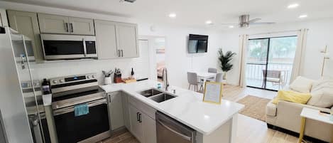 A modern kitchen with built-in appliances, a dining area with a table and chairs, and a balcony with a view.