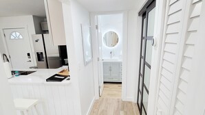 Une cuisine moderne avec des meubles blancs, un plancher en bois et un îlot central.