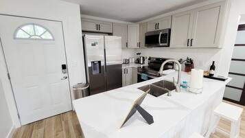 A modern kitchen with stainless steel appliances, a built-in microwave, and a large island with a sink.